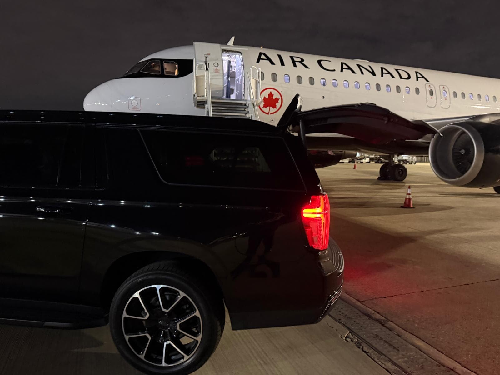 Blitz Limo black Chevrolet Suburban beside a plane at night